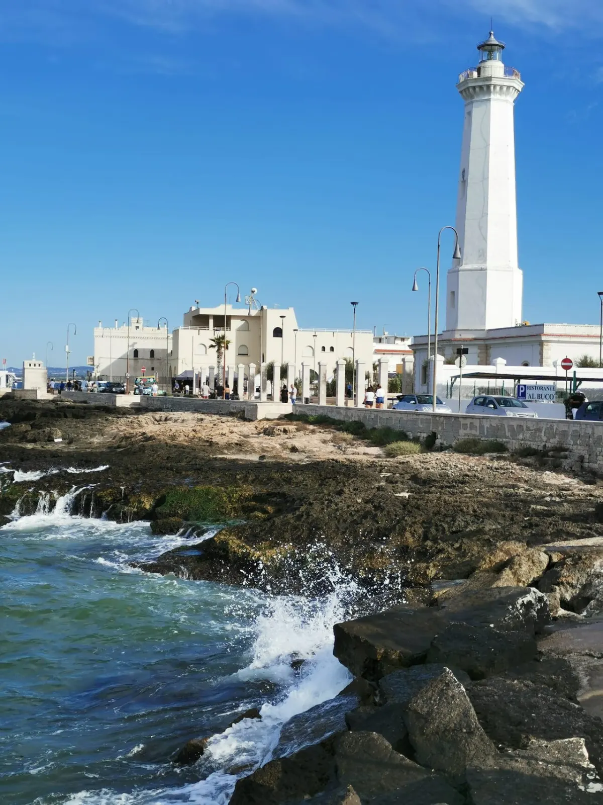 Der weiße Leuchtturm von Torre Canne über der felsigen Küste.